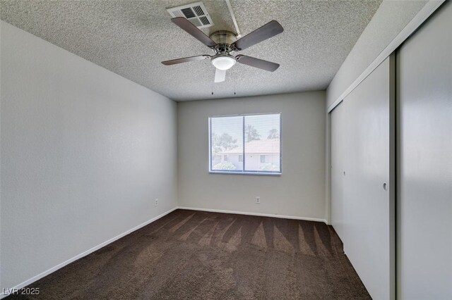 1013 Falconhead Ln Unit 202, Las Vegas, NV 89128 - unfurnished bedroom featuring dark colored carpet, a closet, a textured ceiling, and ceiling fan
