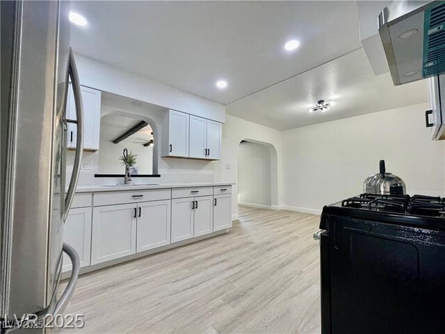 4324 El Conlon Ave, Las Vegas, NV 89102 - kitchen featuring freestanding refrigerator, black range with gas stovetop, arched walkways, light wood-style floors, and light countertops