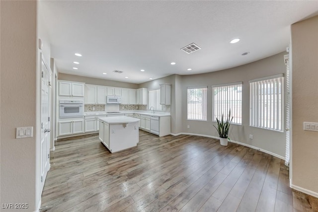 7606 Kenwood Hills Ct, Las Vegas, NV 89131 - kitchen with white appliances, light countertops, white cabinetry, a kitchen island, and light wood-type flooring
