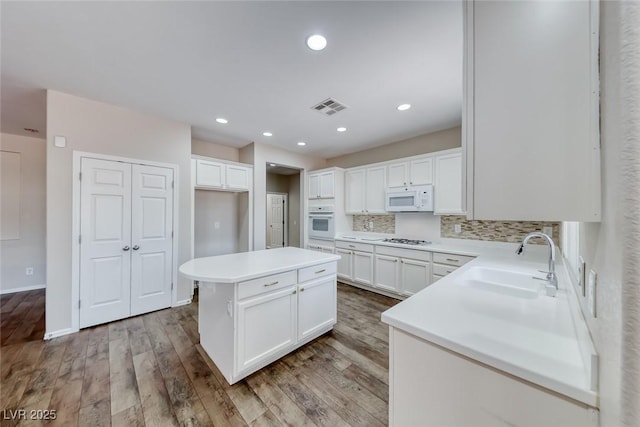 7606 Kenwood Hills Ct, Las Vegas, NV 89131 - kitchen featuring white appliances, white cabinets, a center island, backsplash, and recessed lighting