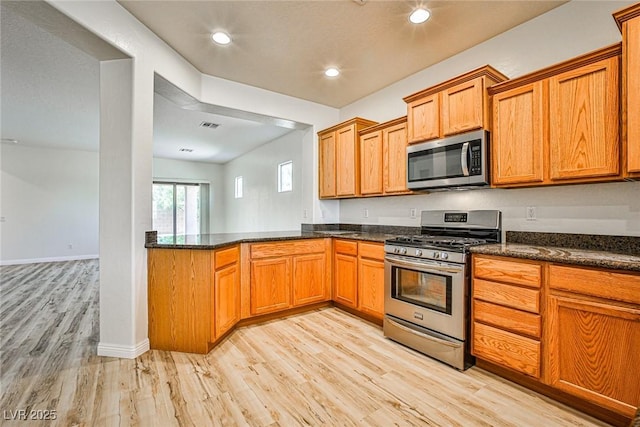 5967 Sun Appello Ave, Las Vegas, NV 89122 - kitchen featuring stainless steel appliances, light wood-style floors, brown cabinets, dark stone counters, and recessed lighting