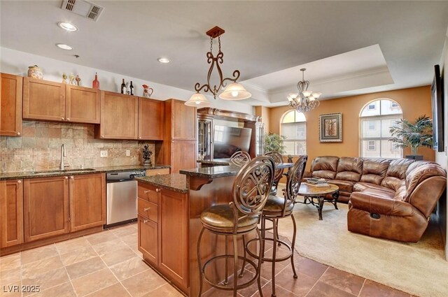 2405 W Serene Ave Unit 612, Las Vegas, NV 89123 - kitchen featuring stainless steel dishwasher, a tray ceiling, a breakfast bar, brown cabinetry, and open floor plan