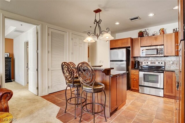 2405 W Serene Ave Unit 612, Las Vegas, NV 89123 - kitchen featuring stainless steel appliances, a kitchen bar, brown cabinets, a center island, and recessed lighting