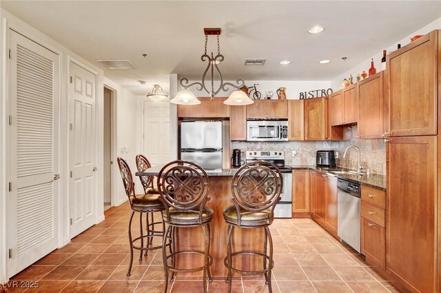 2405 W Serene Ave Unit 612, Las Vegas, NV 89123 - kitchen with appliances with stainless steel finishes, a kitchen breakfast bar, dark stone countertops, backsplash, and a kitchen island