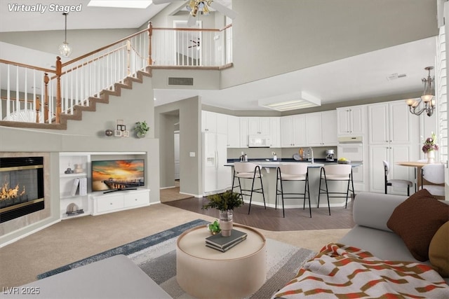 8612 Chiquita Dr, Las Vegas, NV 89128 - living room featuring a glass covered fireplace, ceiling fan, a towering ceiling, and a chandelier