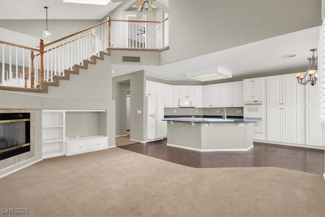 8612 Chiquita Dr, Las Vegas, NV 89128 - kitchen with dark colored carpet, open floor plan, white appliances, ceiling fan, and white cabinetry