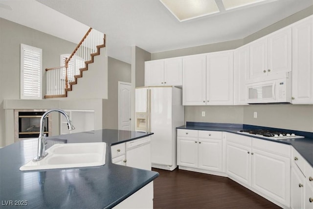 8612 Chiquita Dr, Las Vegas, NV 89128 - kitchen with white appliances, dark countertops, white cabinets, and dark wood-style floors