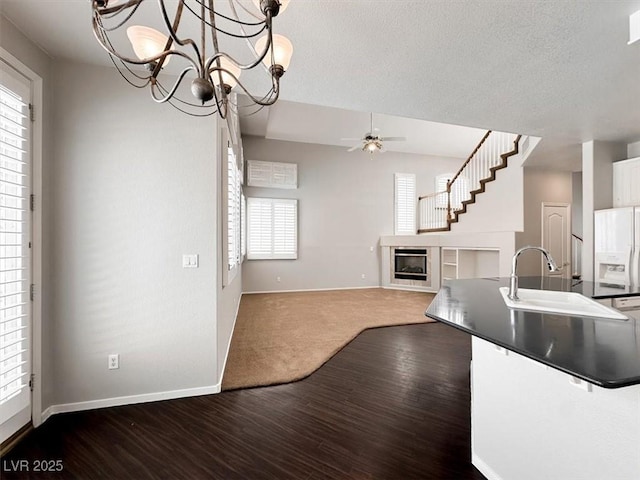 8612 Chiquita Dr, Las Vegas, NV 89128 - kitchen featuring healthy amount of natural light, a glass covered fireplace, ceiling fan, dark countertops, and a textured ceiling