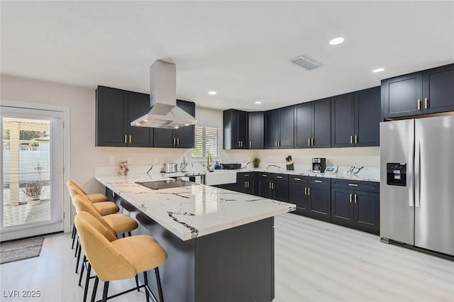 3047 Van Buskirk Cir, Las Vegas, NV 89121 - kitchen featuring stainless steel refrigerator with ice dispenser, island exhaust hood, a breakfast bar, light stone countertops, and light wood finished floors