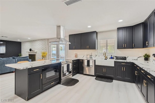 3047 Van Buskirk Cir, Las Vegas, NV 89121 - kitchen featuring island range hood, stainless steel appliances, a peninsula, light wood-type flooring, and open floor plan