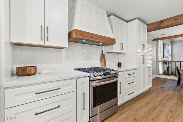 8820 Fall Green Ave, Las Vegas, NV 89129 - kitchen featuring stainless steel range with gas stovetop, custom range hood, light wood-style floors, white cabinets, and backsplash