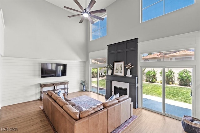 8820 Fall Green Ave, Las Vegas, NV 89129 - living area with a towering ceiling, a glass covered fireplace, a ceiling fan, and wood finished floors