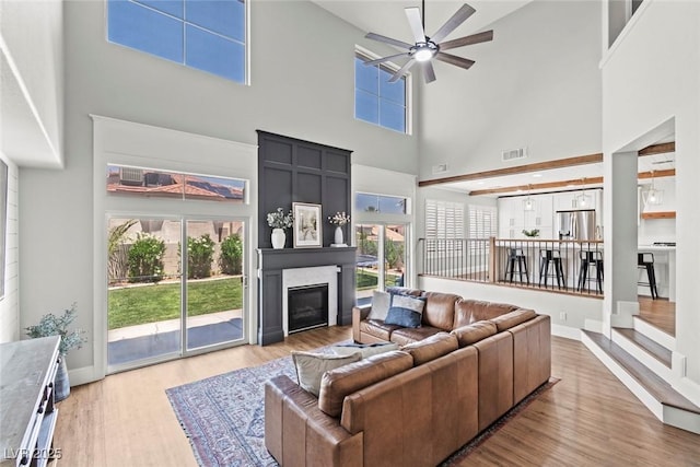 8820 Fall Green Ave, Las Vegas, NV 89129 - living area with a towering ceiling, a ceiling fan, a glass covered fireplace, and wood finished floors