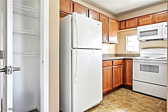 2101 Sealion Dr Unit 108, Las Vegas, NV 89128 - kitchen with white appliances, brown cabinetry, and light tile patterned floors
