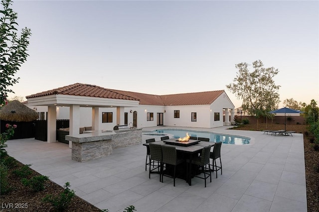 7745 Radcliff St, Las Vegas, NV 89123 - back of property at dusk featuring a patio, a fire pit, a tile roof, and stucco siding