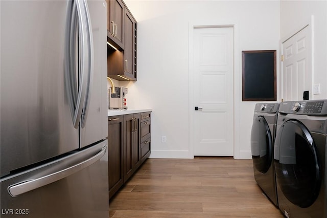 7745 Radcliff St, Las Vegas, NV 89123 - laundry area with washer and clothes dryer, light wood-type flooring, and cabinet space