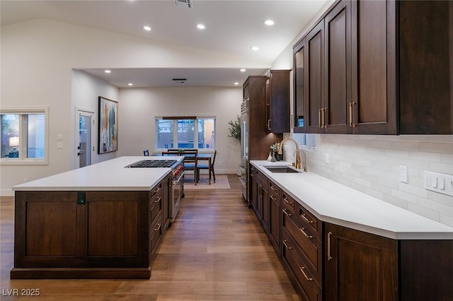 7745 Radcliff St, Las Vegas, NV 89123 - kitchen with lofted ceiling, a center island, wood finished floors, dark brown cabinetry, and decorative backsplash