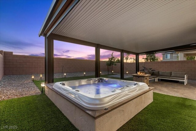 8013 Green River Knob St, Las Vegas, NV 89113 - patio terrace at dusk with a hot tub, a patio, a fenced backyard, and an outdoor living space with a fire pit