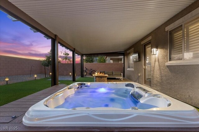 8013 Green River Knob St, Las Vegas, NV 89113 - patio terrace at dusk with a hot tub, a fenced backyard, and a fire pit