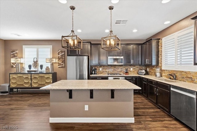 8013 Green River Knob St, Las Vegas, NV 89113 - kitchen featuring stainless steel appliances, a chandelier, a kitchen island, dark brown cabinets, and a breakfast bar area