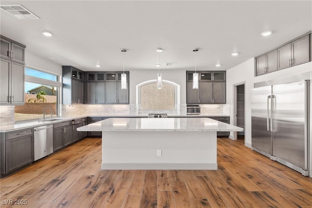 8753 Mann St, Las Vegas, NV 89139 - kitchen with appliances with stainless steel finishes, tasteful backsplash, a center island, light wood finished floors, and recessed lighting