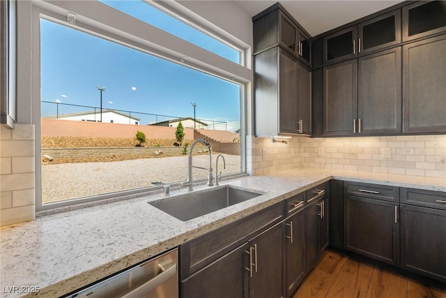 8753 Mann St, Las Vegas, NV 89139 - kitchen with stainless steel dishwasher, dark wood-style flooring, light stone countertops, glass insert cabinets, and backsplash