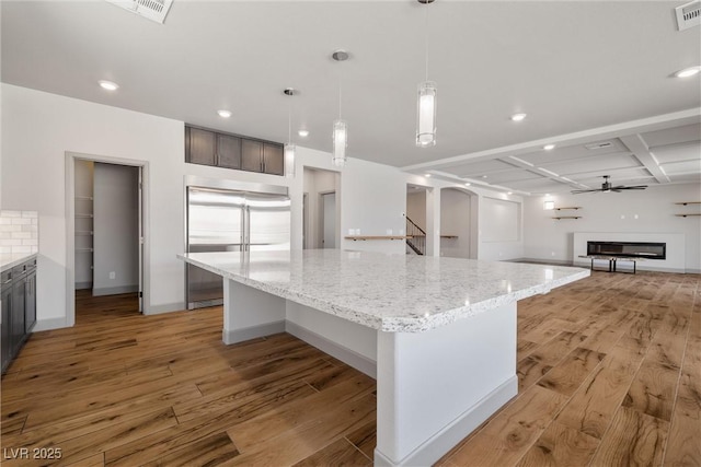 8753 Mann St, Las Vegas, NV 89139 - kitchen featuring stainless steel built in fridge, light wood-style flooring, light stone countertops, a spacious island, and recessed lighting