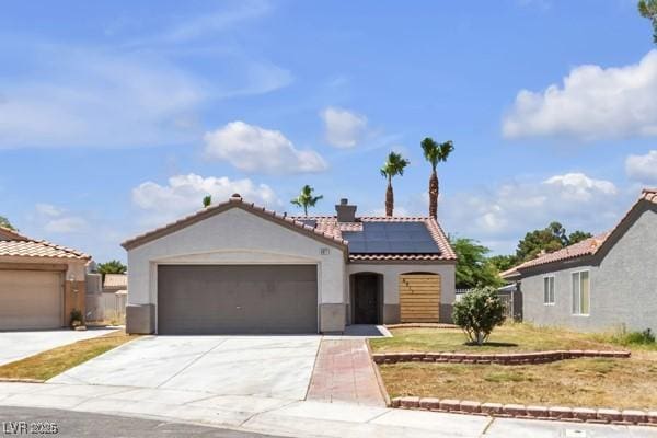 4911 Rancho Domingo Ct, North Las Vegas, NV 89031 - mediterranean / spanish house featuring stucco siding, a tiled roof, roof mounted solar panels, driveway, and an attached garage