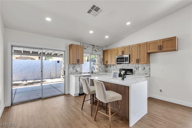 4911 Rancho Domingo Ct, North Las Vegas, NV 89031 - kitchen featuring appliances with stainless steel finishes, decorative backsplash, lofted ceiling, light countertops, and recessed lighting