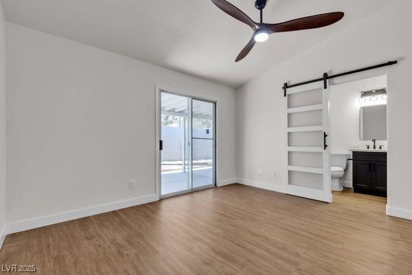 4911 Rancho Domingo Ct, North Las Vegas, NV 89031 - unfurnished bedroom featuring a barn door, access to outside, light wood finished floors, connected bathroom, and ceiling fan