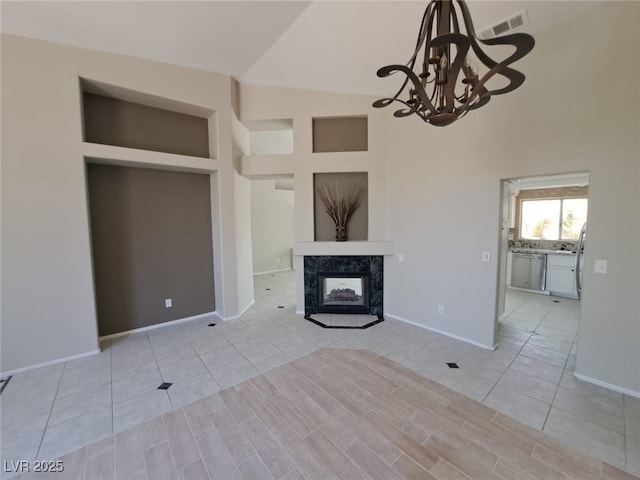 13 Desert Dawn Ln, Henderson, NV 89074 - unfurnished living room featuring high vaulted ceiling, a chandelier, a premium fireplace, and light tile patterned floors