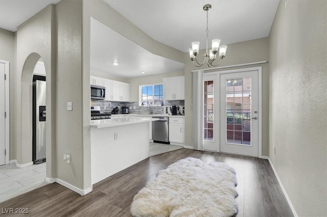 10553 Pine Glen Ave Unit 101, Las Vegas, NV 89144 - kitchen featuring stainless steel appliances, arched walkways, white cabinets, decorative backsplash, and light countertops