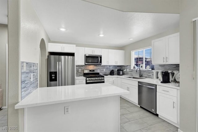 10553 Pine Glen Ave Unit 101, Las Vegas, NV 89144 - kitchen featuring stainless steel appliances, decorative backsplash, white cabinetry, arched walkways, and a kitchen island