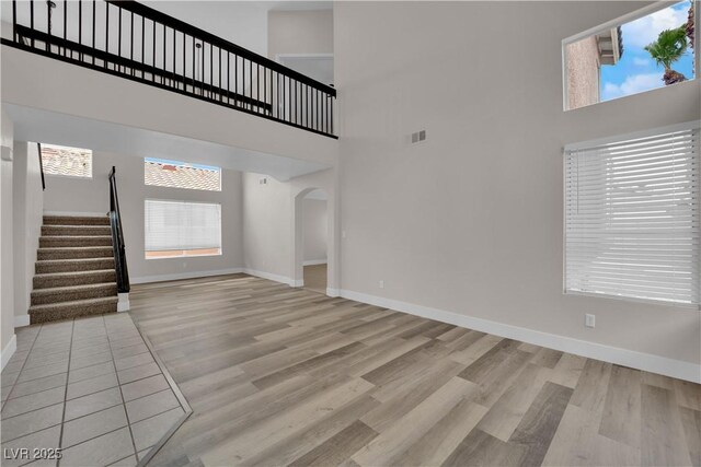 8379 Drop Camp St, Las Vegas, NV 89123 - unfurnished living room featuring a high ceiling, plenty of natural light, stairs, and light wood-style floors