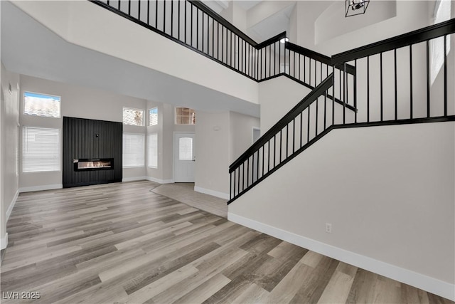 8379 Drop Camp St, Las Vegas, NV 89123 - unfurnished living room featuring stairway, a glass covered fireplace, a towering ceiling, and wood finished floors