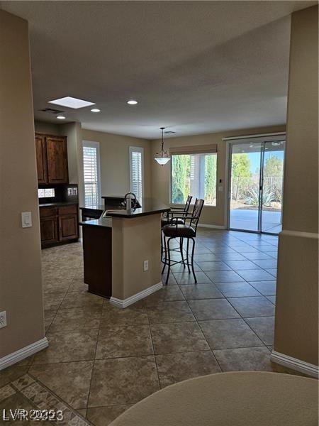 5110 Silenzio St, Las Vegas, NV 89135 - kitchen with dark countertops, dark tile patterned flooring, recessed lighting, a breakfast bar, and decorative light fixtures
