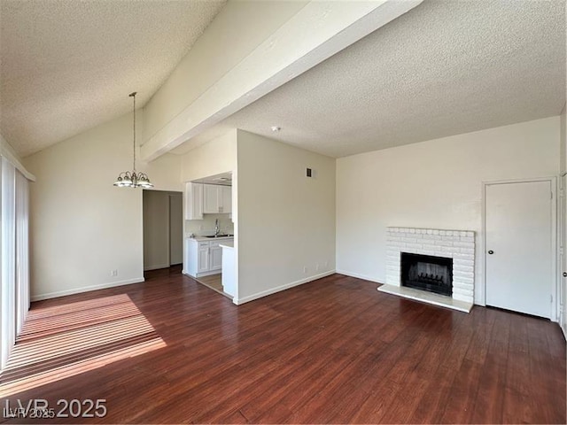 4230 Gannet Cir Unit 216, Las Vegas, NV 89103 - unfurnished living room featuring dark wood-type flooring, a brick fireplace, vaulted ceiling, a chandelier, and a textured ceiling