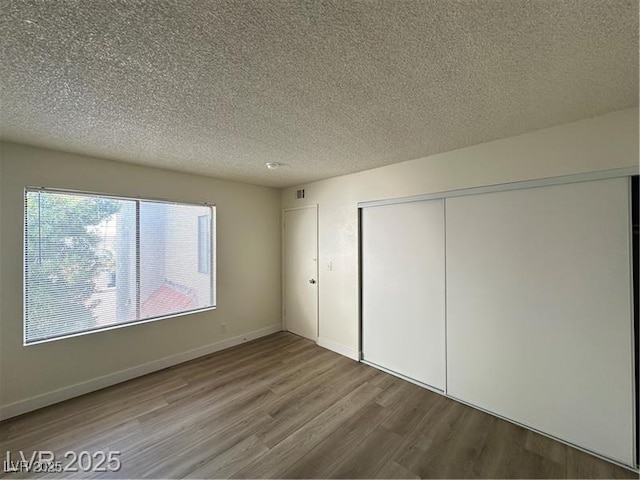 4230 Gannet Cir Unit 216, Las Vegas, NV 89103 - unfurnished bedroom with wood finished floors, a textured ceiling, and a closet