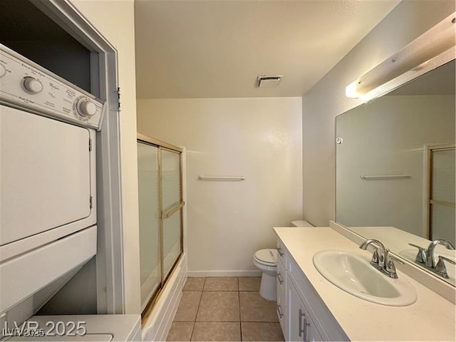 4230 Gannet Cir Unit 216, Las Vegas, NV 89103 - bathroom featuring vanity, tile patterned flooring, stacked washer and clothes dryer, and combined bath / shower with glass door