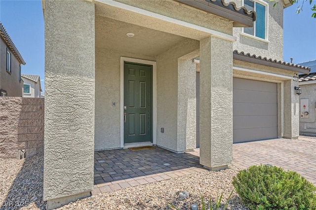 4364 Contour Bend Ave, North Las Vegas, NV 89084 - view of exterior entry with stucco siding, an attached garage, and decorative driveway