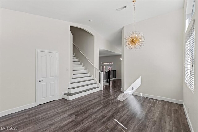 11484 Roncat Ct, Las Vegas, NV 89141 - empty room with plenty of natural light, dark wood-type flooring, stairs, a chandelier, and high vaulted ceiling