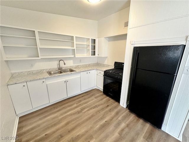 4924 Carmen Blvd, Las Vegas, NV 89108 - kitchen with open shelves, black appliances, light wood-style floors, white cabinets, and light stone counters