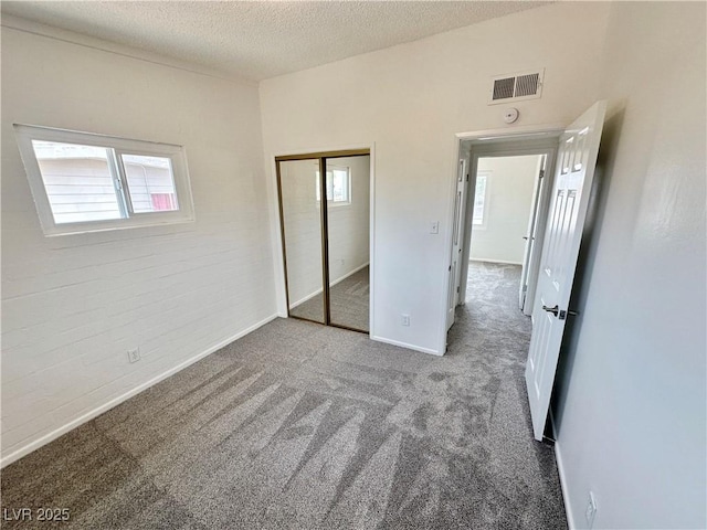 4924 Carmen Blvd, Las Vegas, NV 89108 - unfurnished bedroom with carpet, multiple windows, a textured ceiling, a closet, and brick wall