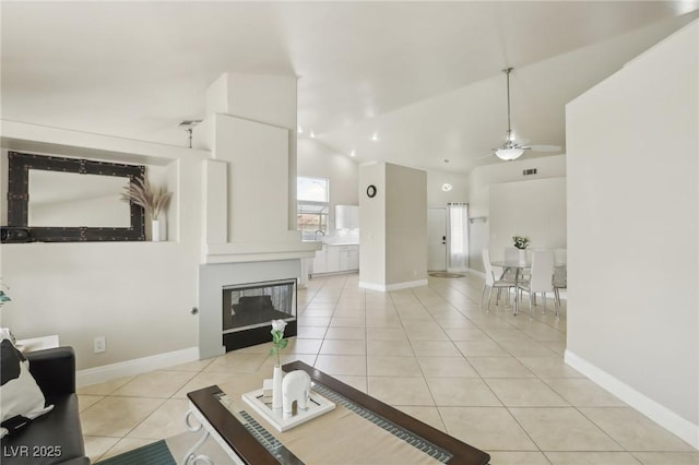 4753 Carefree Dr, Las Vegas, NV 89122 - living area with light tile patterned flooring, ceiling fan, vaulted ceiling, and a glass covered fireplace