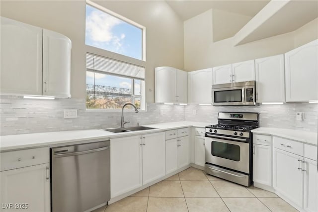 4753 Carefree Dr, Las Vegas, NV 89122 - kitchen featuring appliances with stainless steel finishes, light tile patterned flooring, a high ceiling, white cabinetry, and tasteful backsplash