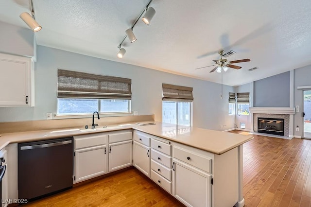 8309 Windrush Ave, Las Vegas, NV 89117 - kitchen with stainless steel dishwasher, a peninsula, white cabinets, ceiling fan, and light wood-type flooring