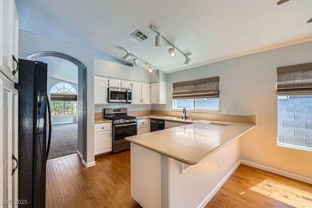 8309 Windrush Ave, Las Vegas, NV 89117 - kitchen with stainless steel appliances, a peninsula, hardwood / wood-style floors, white cabinets, and light countertops