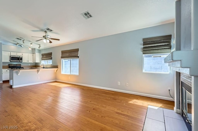 8309 Windrush Ave, Las Vegas, NV 89117 - kitchen with appliances with stainless steel finishes, a breakfast bar, white cabinetry, a peninsula, and plenty of natural light