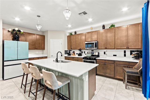 7502 Lush Oasis Ave, Las Vegas, NV 89113 - kitchen with appliances with stainless steel finishes, light countertops, light tile patterned floors, a breakfast bar, and a center island with sink
