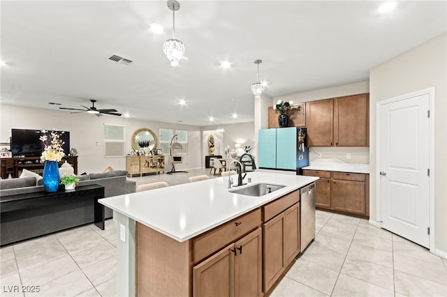 7502 Lush Oasis Ave, Las Vegas, NV 89113 - kitchen featuring stainless steel dishwasher, freestanding refrigerator, light countertops, brown cabinetry, and an island with sink